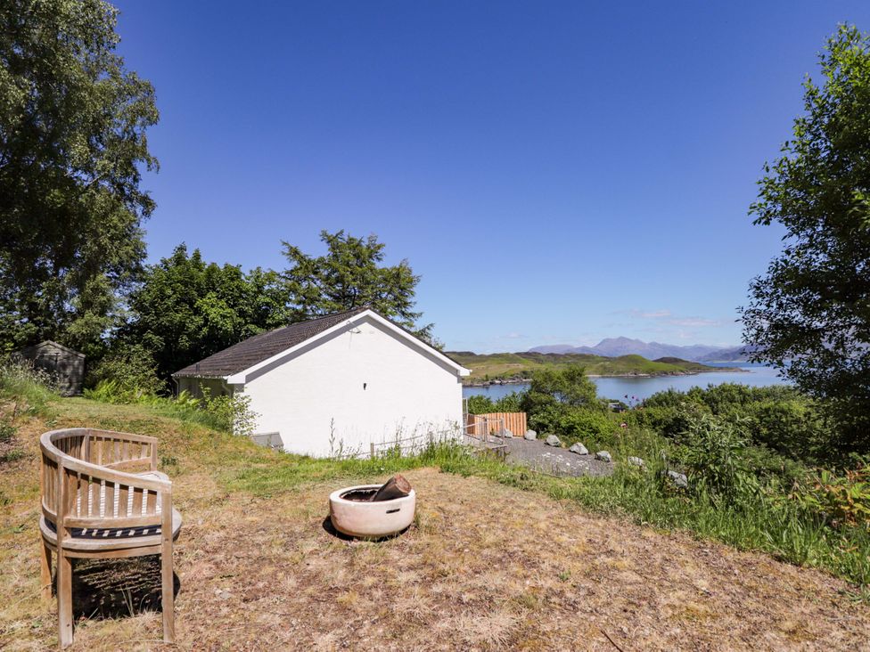 An outdoor area with a house, bench, and fire pit at The Lookout in Saasaig near Broadford