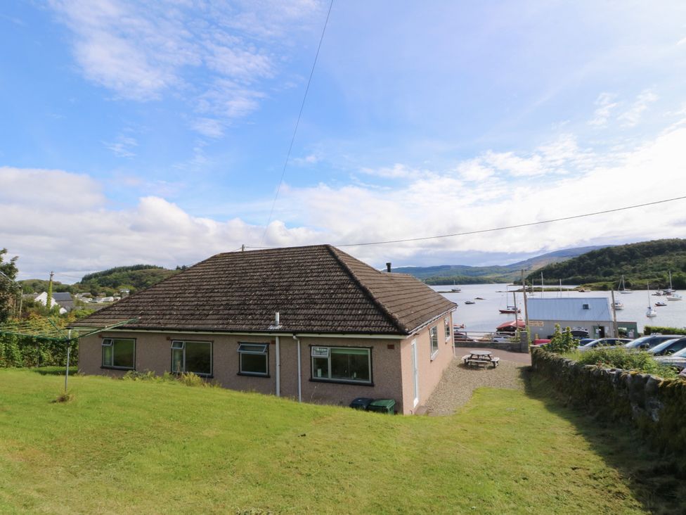 A house with grass and a view of water and boats at Am Bruaich in Tayvallich