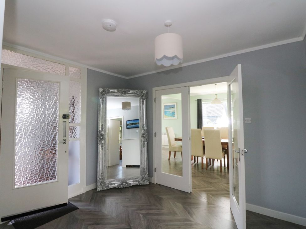A hallway with a mirror and doors leading to the dining room at Am Bruaich in Tayvallich