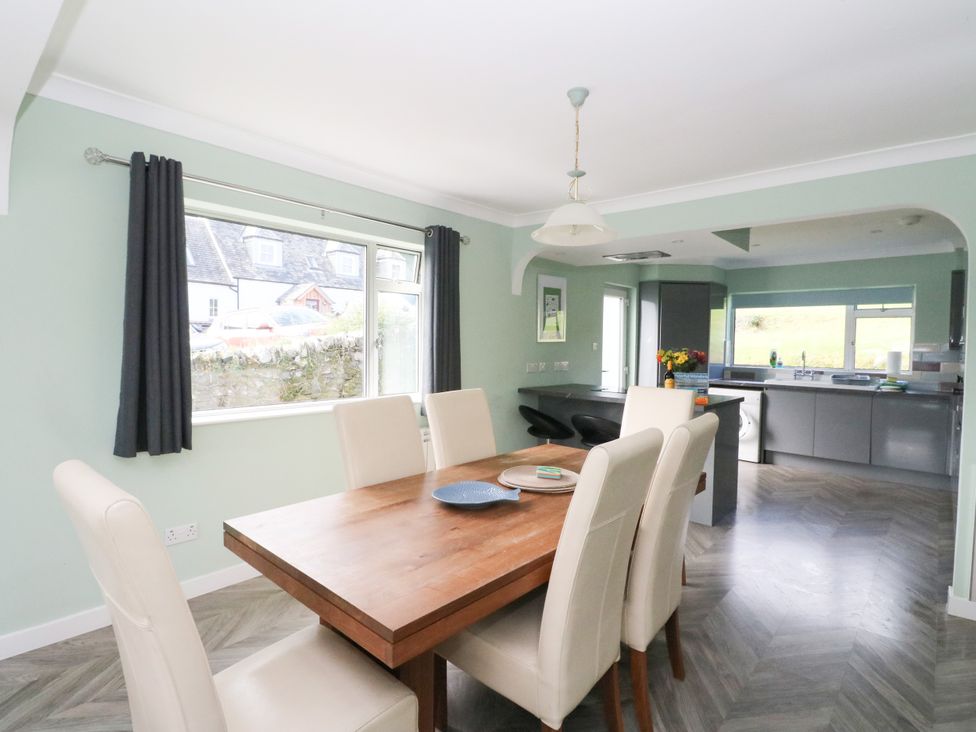 A dining room with a table and chairs leading to a kitchen at Am Bruaich in Tayvallich