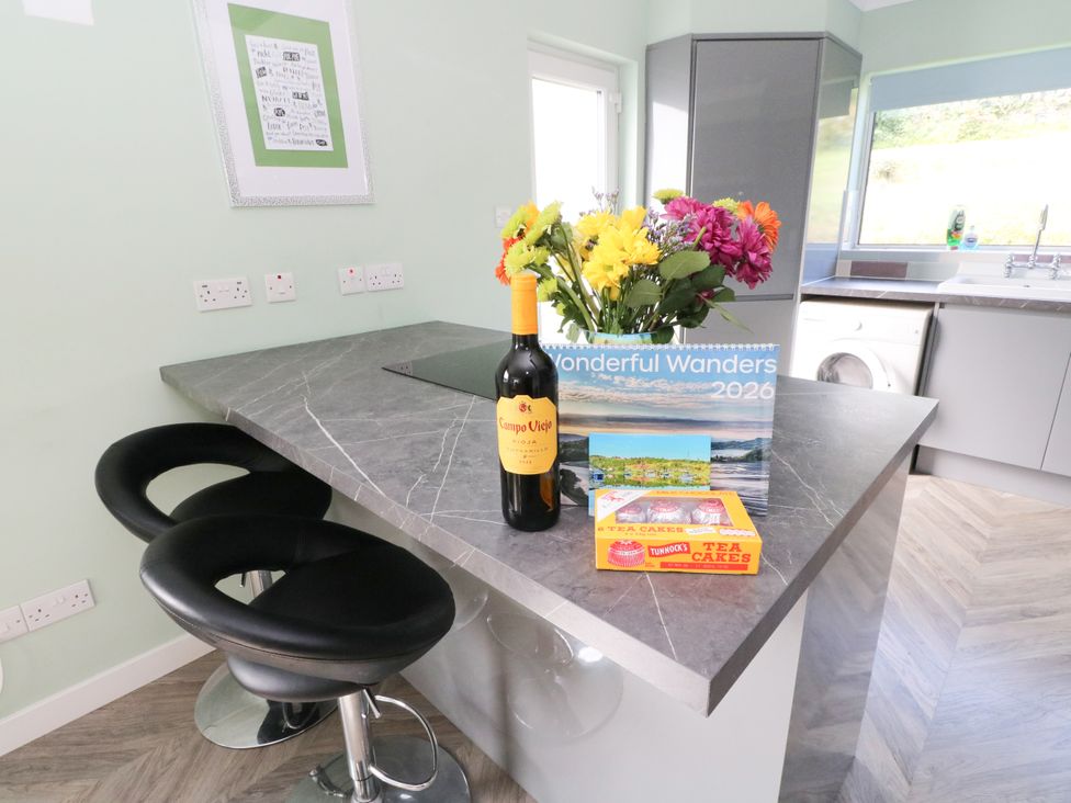 A kitchen with a wine bottle flowers and a calendar at Am Bruaich Tayvallich