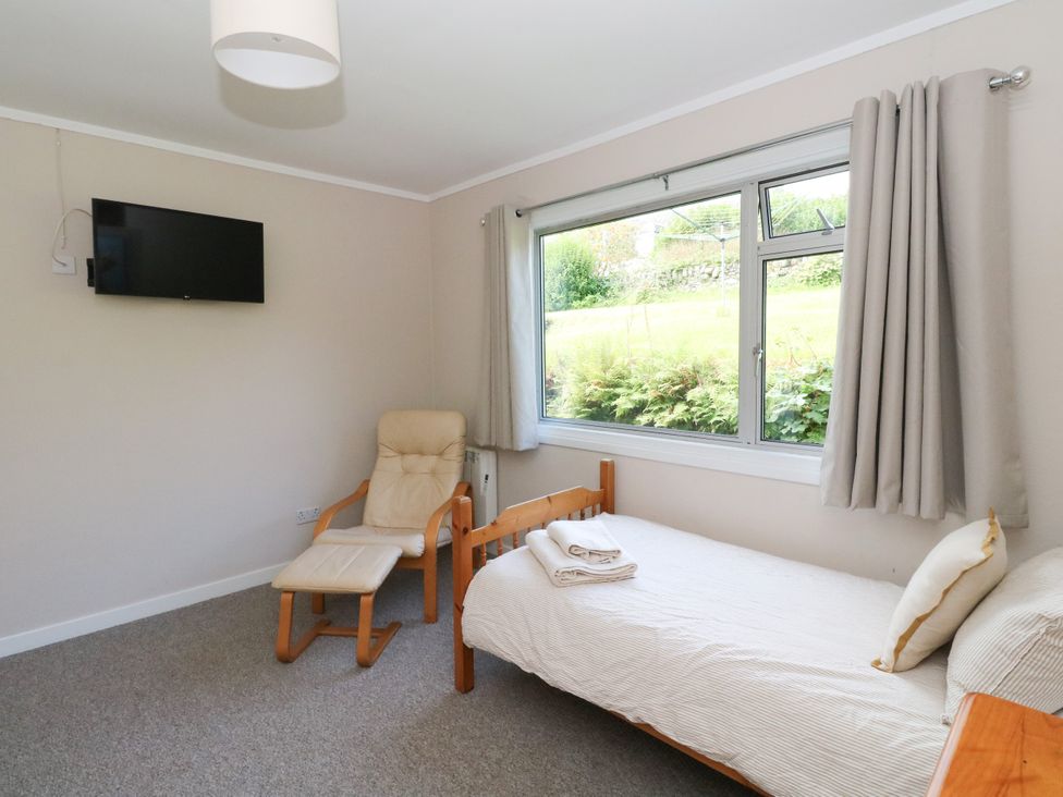 A bedroom with a bed and a chair at Am Bruaich in Tayvallich