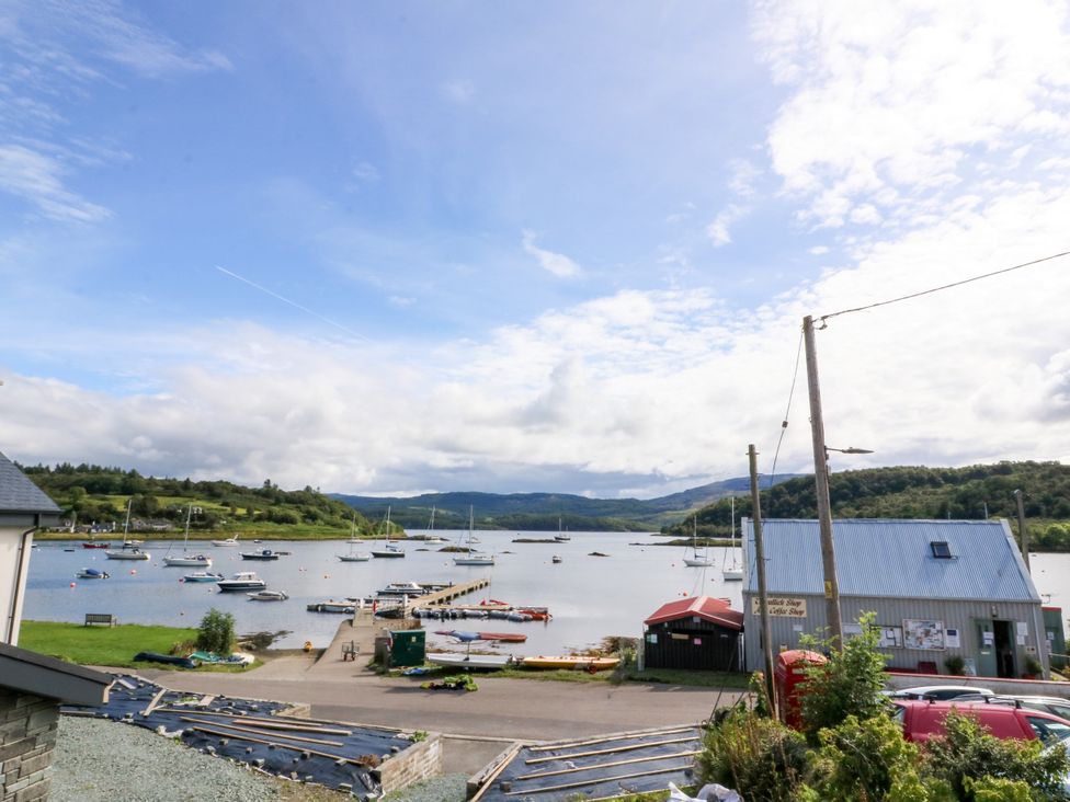 A view of boats at a pier with a building near the water at Am Bruaich Tayvallich