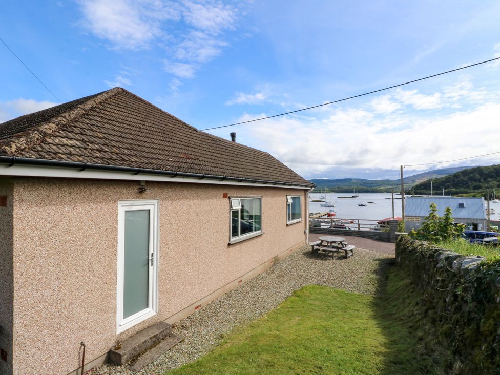 A house with a patio and view of water and boats at Am Bruaich in Tayvallich