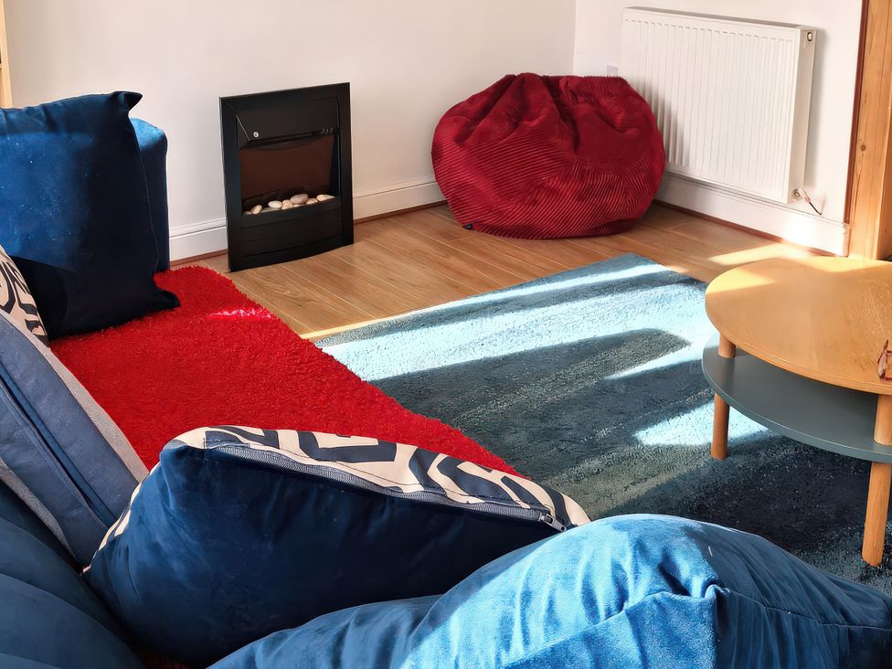 A living room with a couch and a fireplace at Buttercups at Midway in Kington