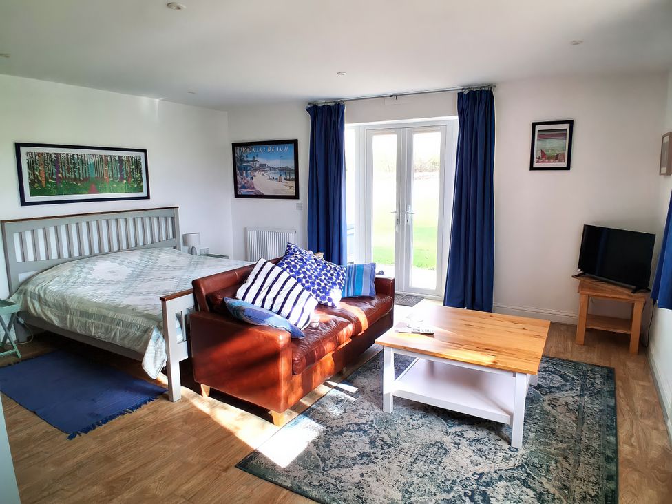 A living room with a bed, sofa, and coffee table at Buttercups at Midway Kington