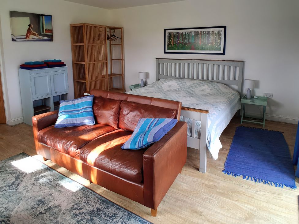 A bedroom with a bed, sofa and wardrobe at Buttercups at Midway Kington