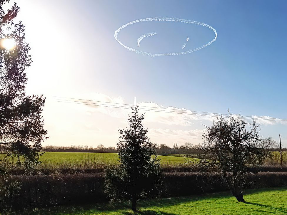 An outdoor photo showing trees and a field under a clear sky at Buttercups at Midway in Kington