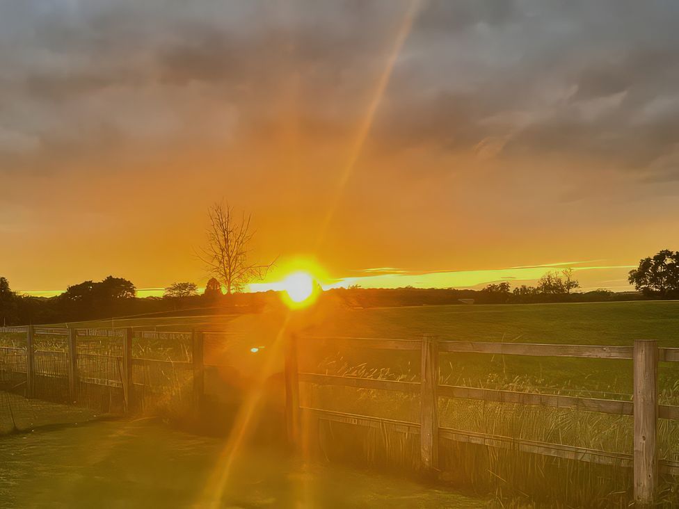 A sunset over a field with a fence at Buttercups at Midway Kington