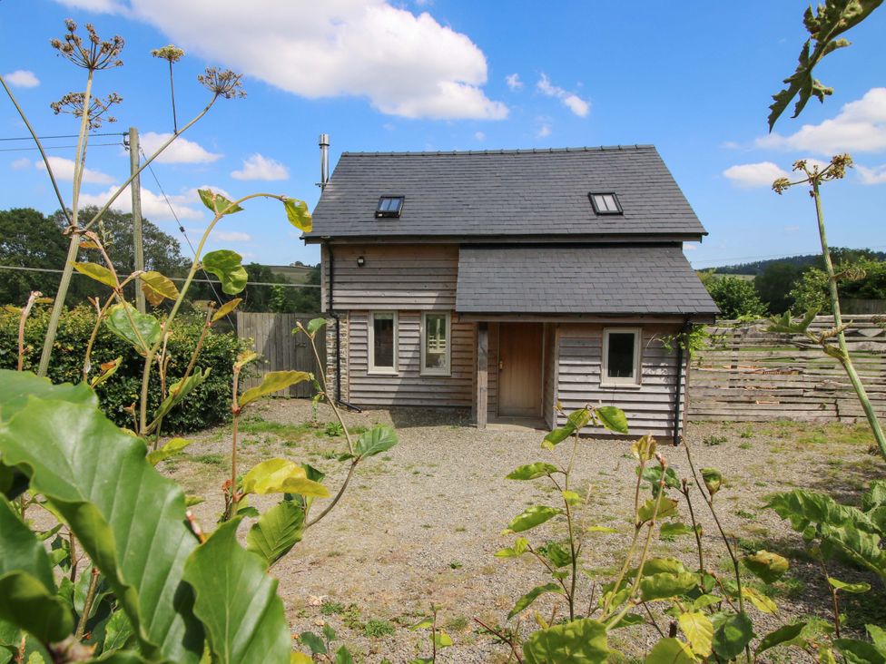 A wooden house with gravel area at Brynlikky Cottage in Chapel Lawn near Bucknell