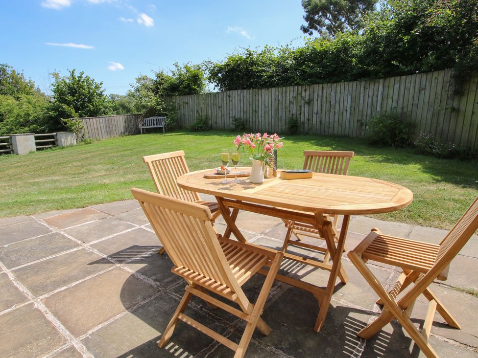 A garden area with a wooden table and chairs at Brynlikky Cottage in Chapel Lawn near Bucknell