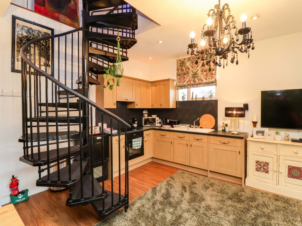 A kitchen with a spiral staircase and various appliances at The Coach House, The Grove in Combe Martin