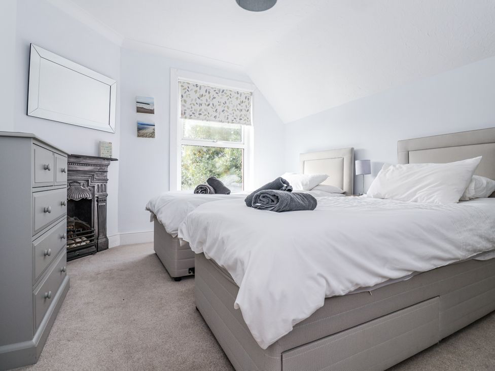 A bedroom with two beds and a mirror at 49 Ulwell Road in Swanage