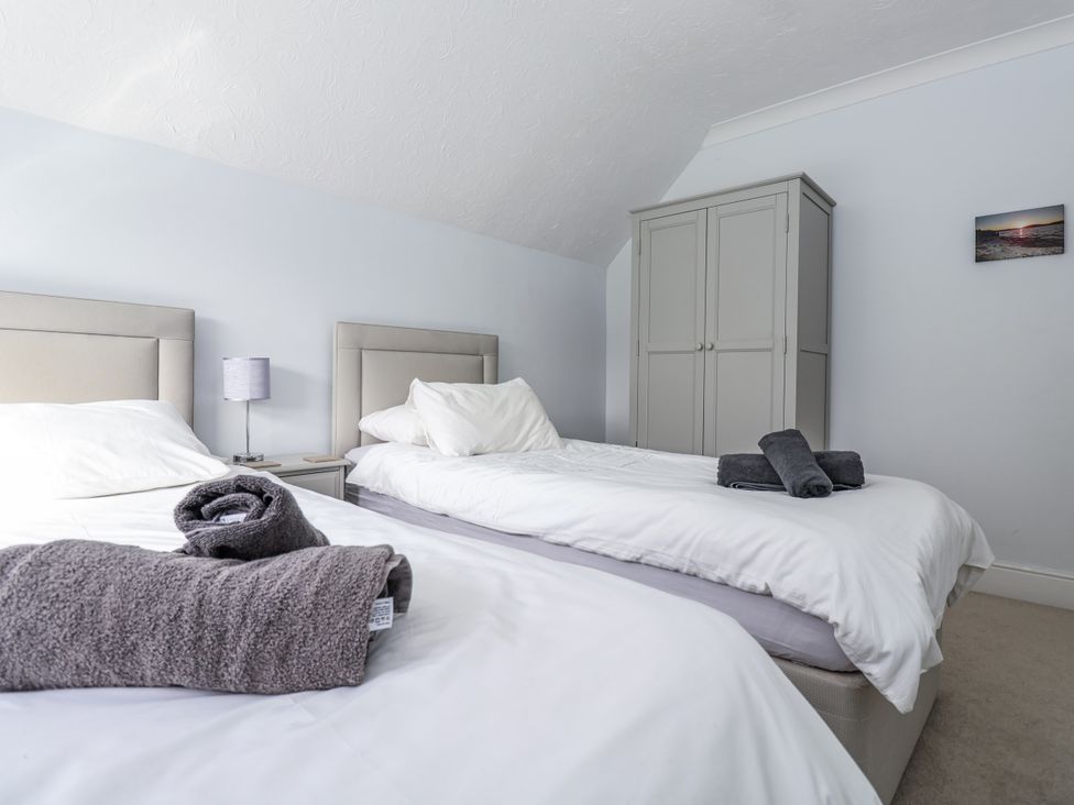 A bedroom with two beds and a wardrobe at 49 Ulwell Road in Swanage