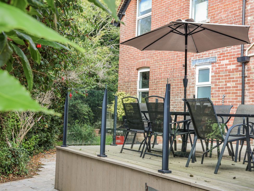 A garden with a table and chairs under an umbrella at 49 Ulwell Road Swanage
