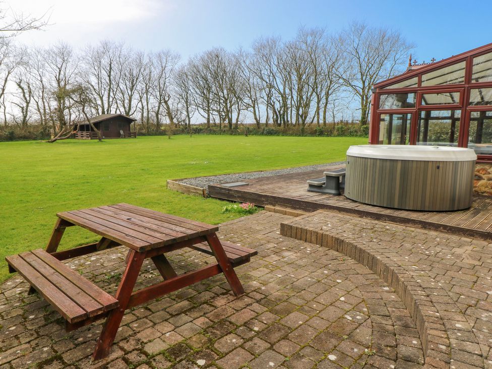 An outdoor area with a picnic table and hot tub at Mountain Farm in Broad Haven