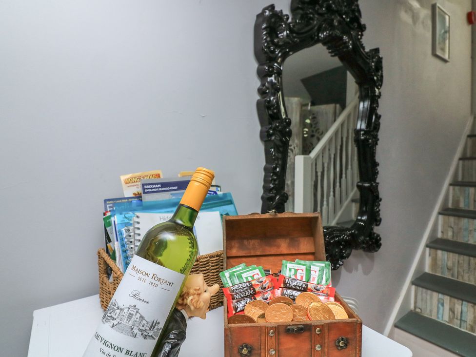 A hallway with a wine bottle and a wooden box filled with snacks at Hidden Treasure in Brixham