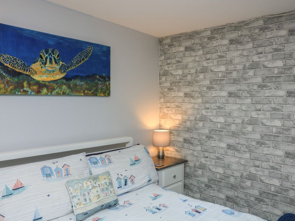 A bedroom with a bed and a bedside lamp at Hidden Treasure in Brixham