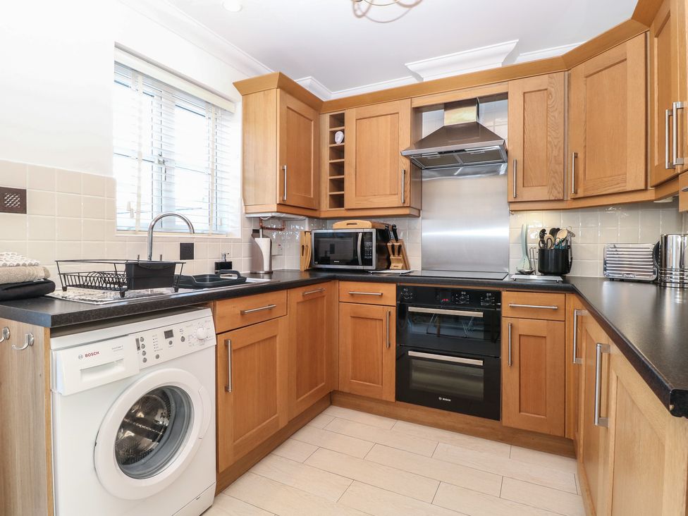 A kitchen with wooden cabinets and appliances at 5 Styleman Road in Hunstanton