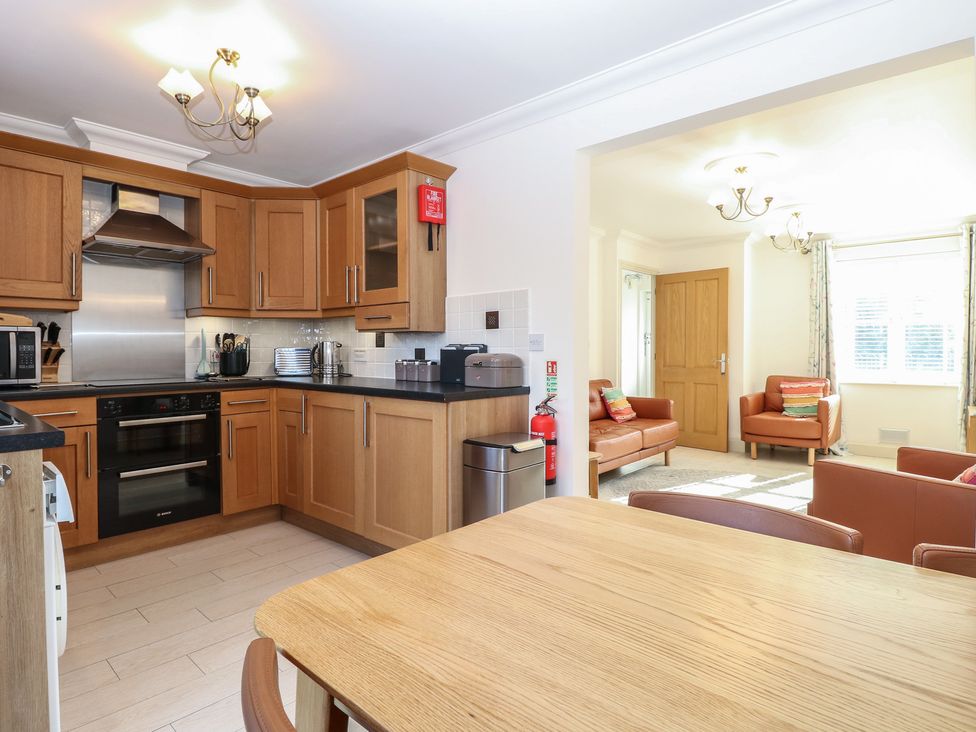 A kitchen with wooden cabinets and a dining table at 5 Styleman Road Hunstanton