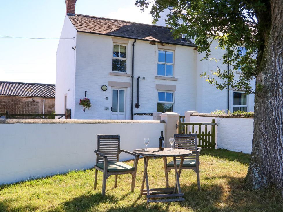 An outdoor seating area with a table and chairs at Tight Lyne Cottage in Longtown