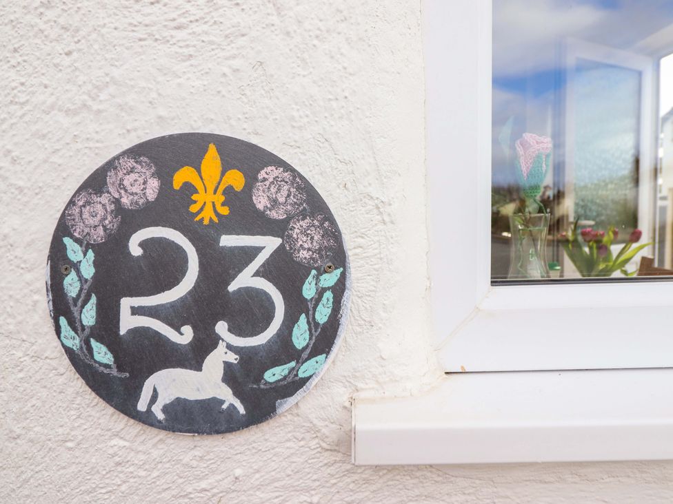 A house number plaque with the number 23 and a unicorn at Castle Cove in Abergele