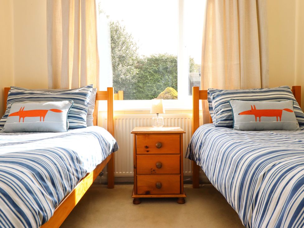 A bedroom with two beds and a bedside table at Castle Cove in Abergele