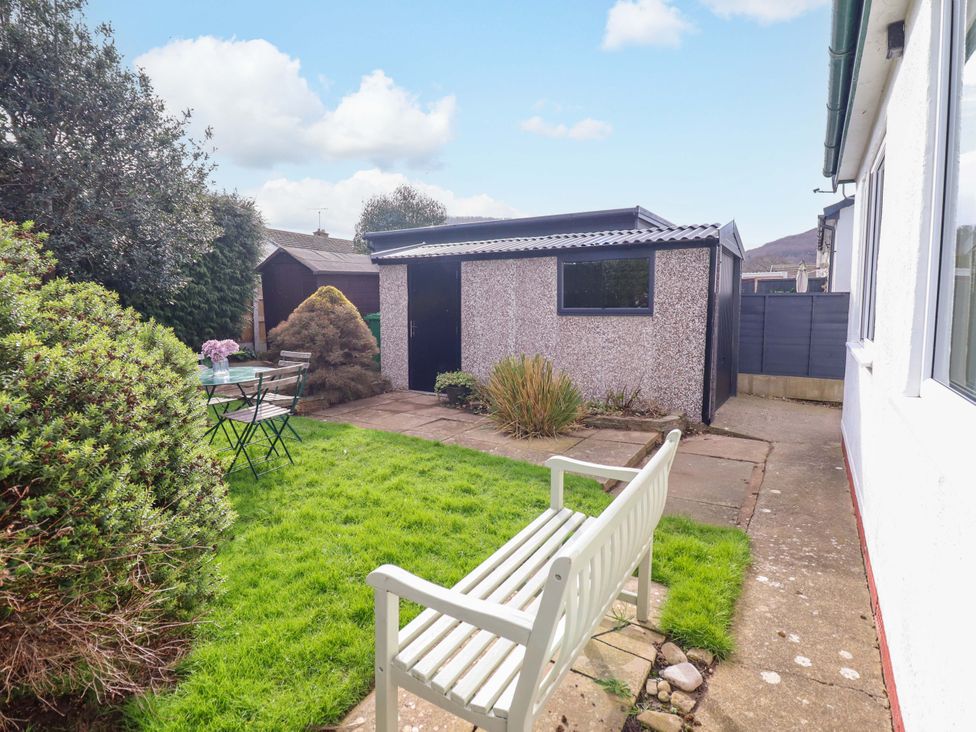 A garden with a shed, table, and chairs at Castle Cove in Abergele