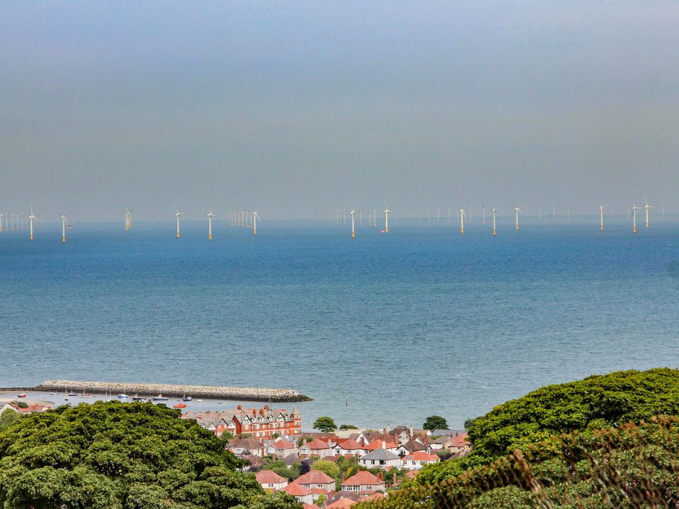 A view of offshore wind turbines and buildings near the sea at Castle Cove in Abergele