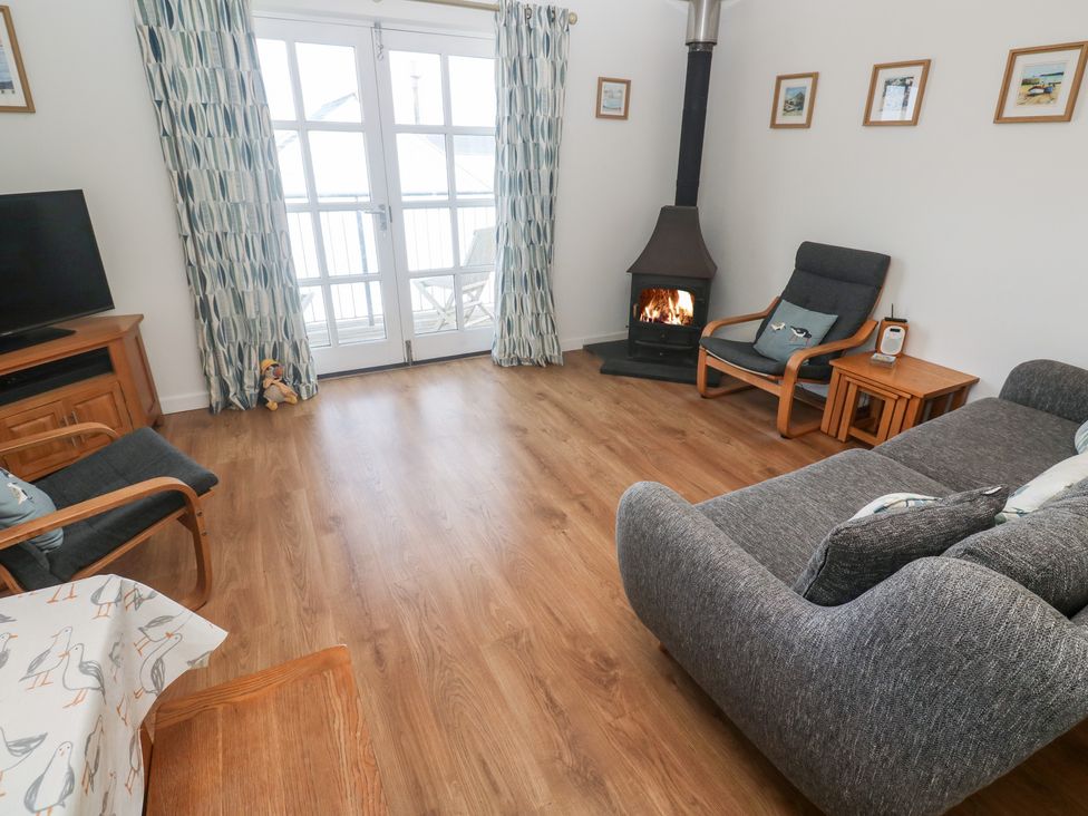 A living room with a wood stove and television at Pilchard Cottage Sennen Cove