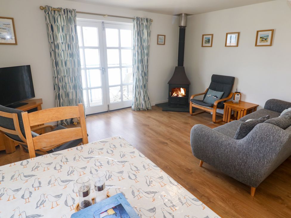 A living room with a television and seating at Pilchard Cottage in Sennen Cove