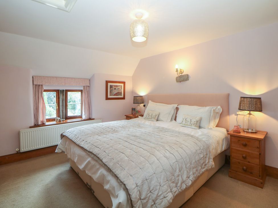 A bedroom with a bed and bedside tables at Green Farm Cottage in Hognaston near Carsington Water