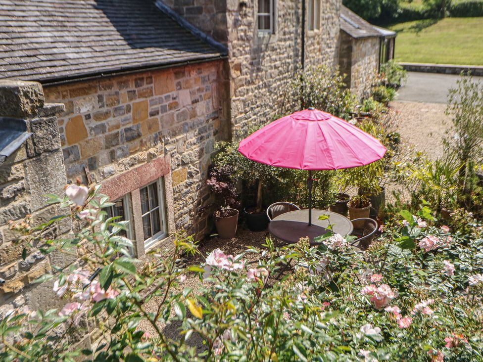 An outdoor seating area with a pink umbrella at Green Farm Cottage in Hognaston near Carsington Water