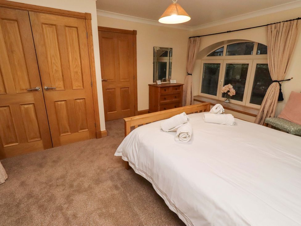 A bedroom with a bed and wooden furniture at Stable D'or in Embleton