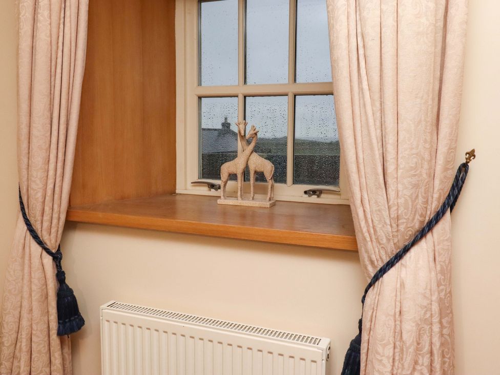 A window with curtains and a decorative figure at Stable D'or in Embleton