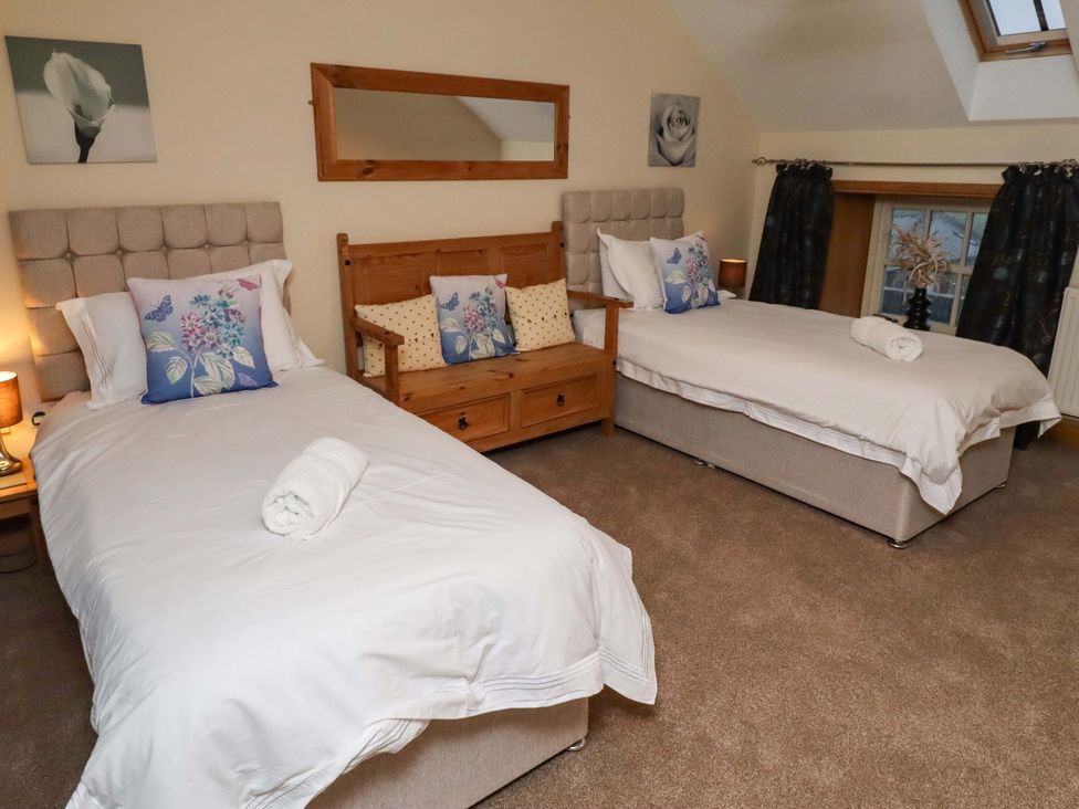 A bedroom with two beds and a wooden sofa at Stable D'or in Embleton