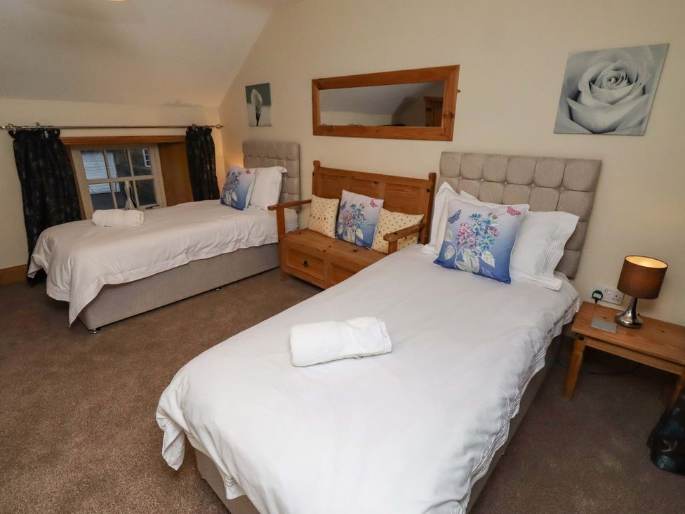 A bedroom with two single beds and a sofa at Stable D'or in Embleton