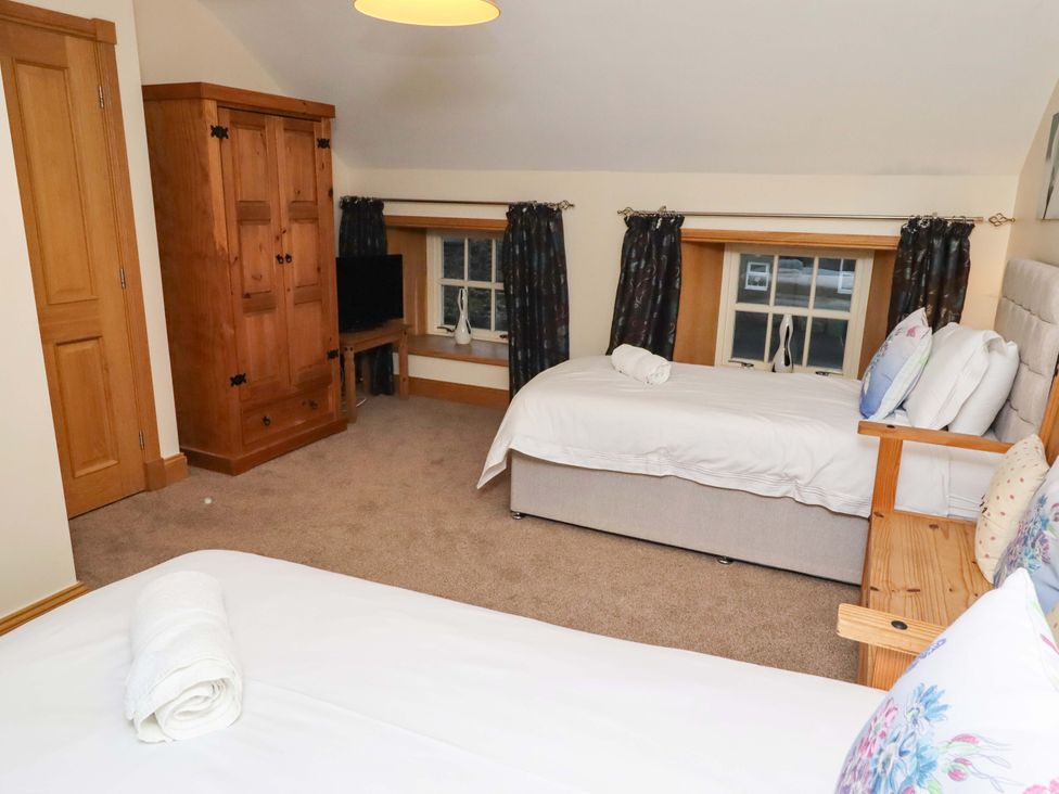A bedroom with beds, a wardrobe, and a television at Stable D'or in Embleton