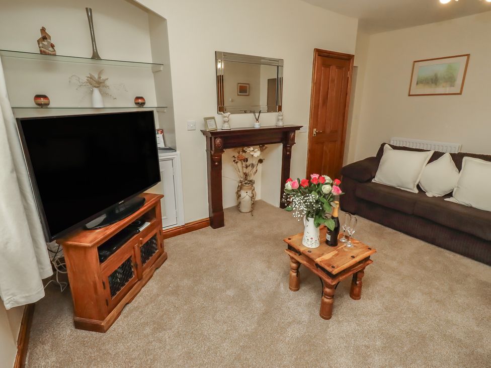 A living room with a television and sofa at The Retreat in Embleton