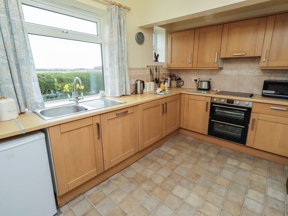 A kitchen with wooden cabinets and appliances at The Retreat in Embleton