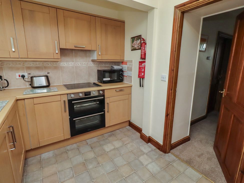 A kitchen with cabinets, stove, microwave and kettle at The Retreat in Embleton