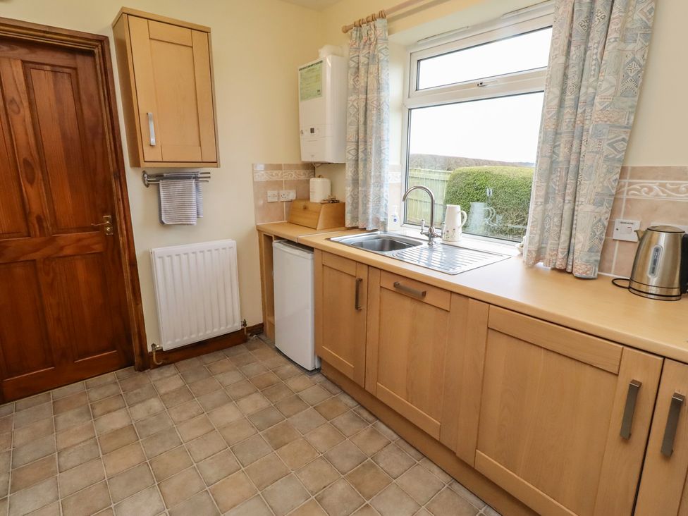 A kitchen with a sink, refrigerator, and window at The Retreat in Embleton