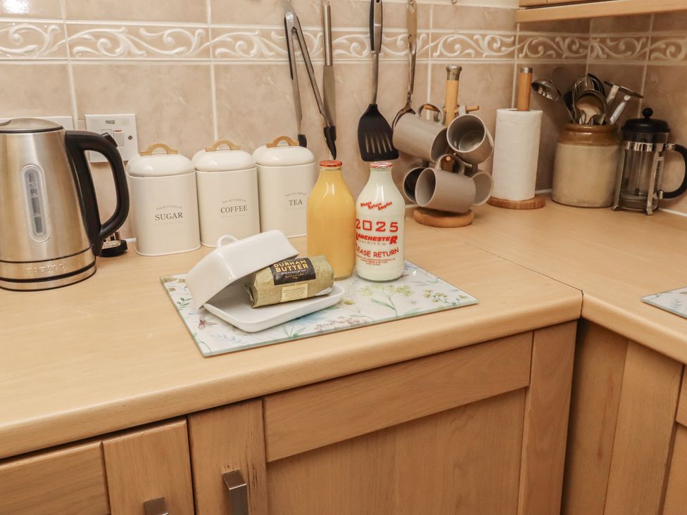 A kitchen countertop with a kettle, containers, and dairy items at The Retreat in Embleton