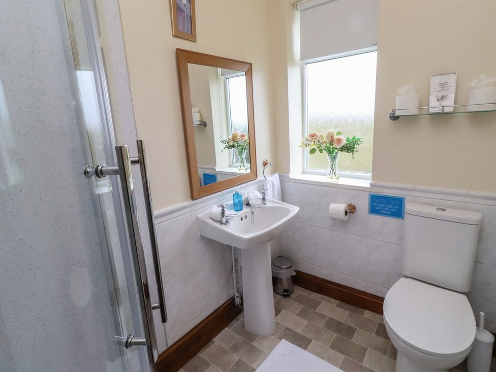 A bathroom with a sink, toilet, shower, and window at The Retreat in Embleton