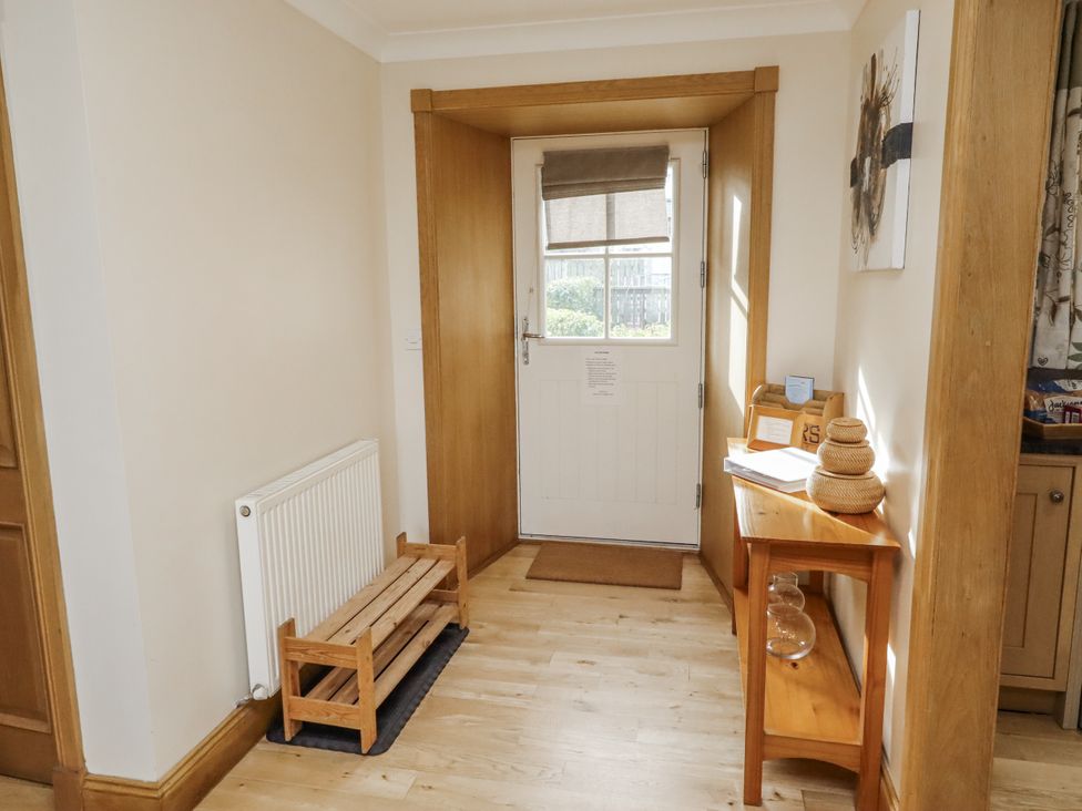 A hallway with a door and bench at Low Croft in Embleton