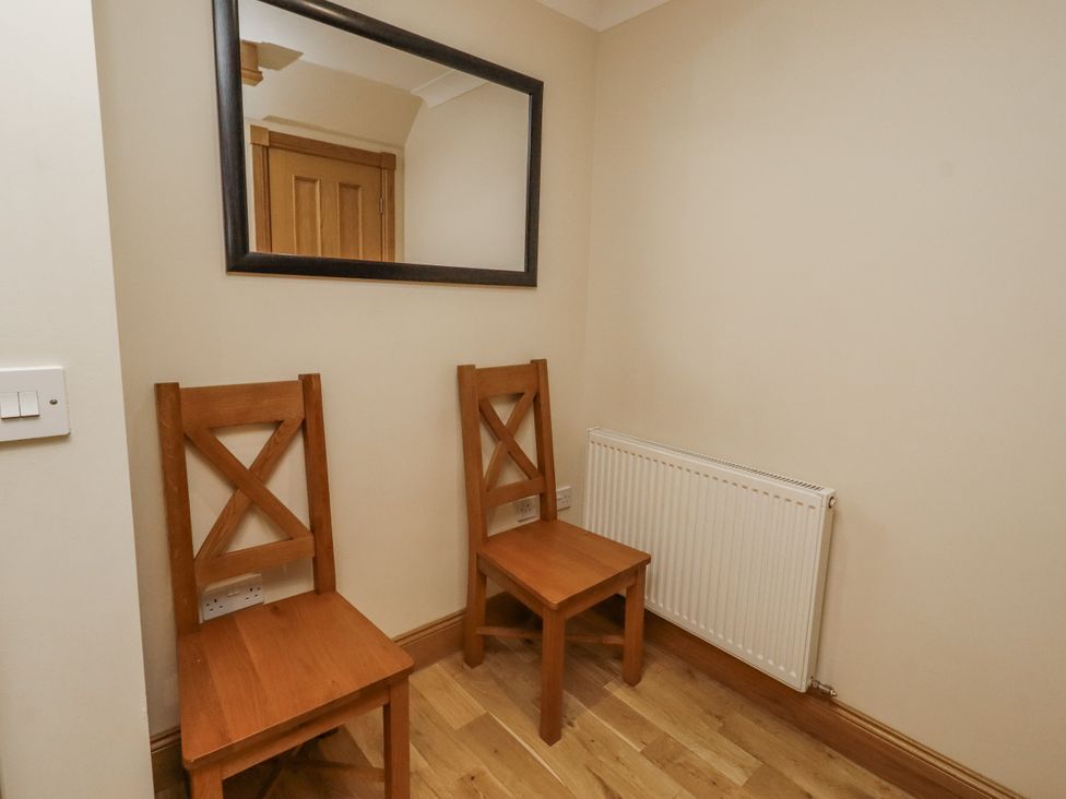 A hallway with two wooden chairs and a mirror at Low Croft in Embleton