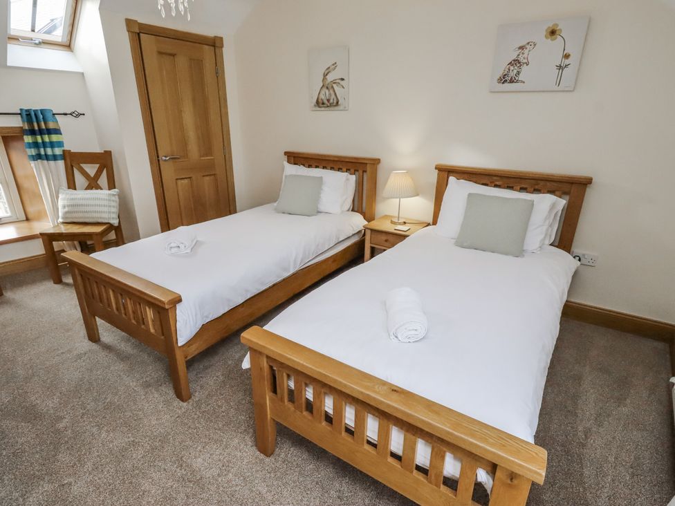 A bedroom with twin beds and a bedside lamp at Low Croft in Embleton