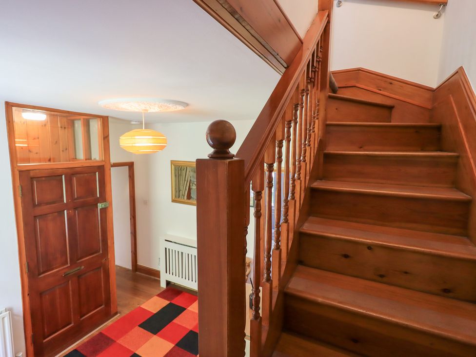 A hallway with a staircase and front door at Drystones in Grasmere