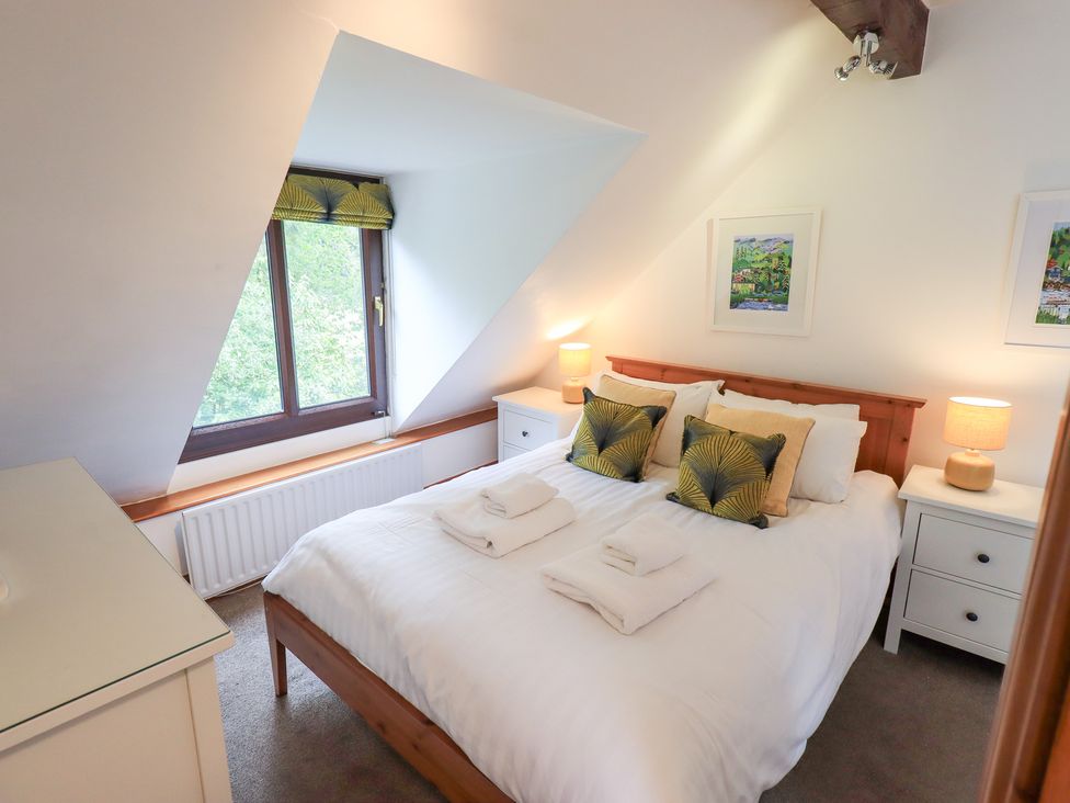 A bedroom with a bed and nightstands at Drystones in Grasmere