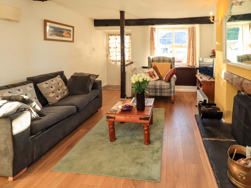 A living room with a sofa, armchair, and television at Buttonhole Cottage in Ambleside